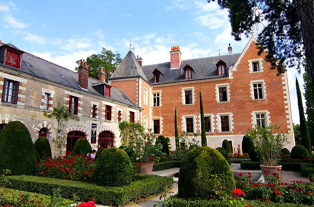 The brick-and-stone manor of Clos Lucé seen from its garden with box hedges and roses
